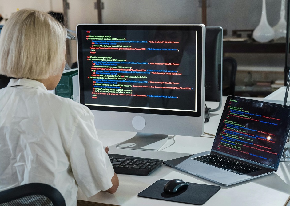 A woman doing coding on a desktop computer and on a laptop | emerging tech roles