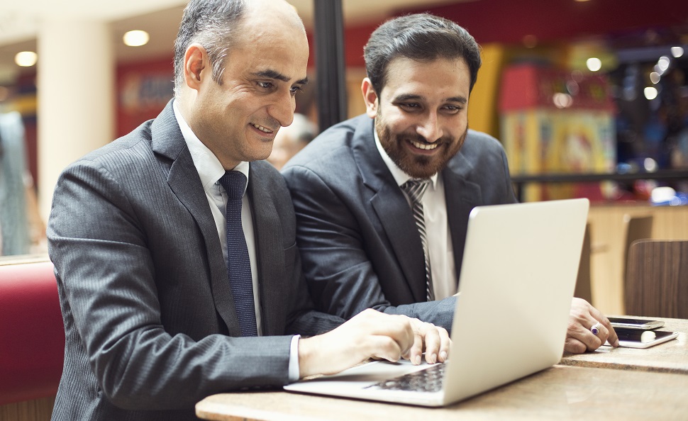 A group of four professionals of different age groups seated and looking at a laptop screen, illustrating an age-inclusive work environment