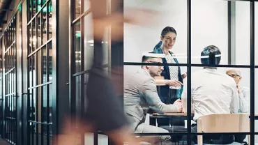 Business meeting in a modern glass-walled office room.