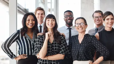 A diverse group of professionals smiling in a bright office setting.