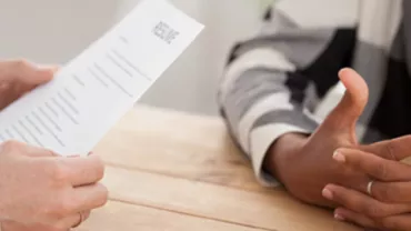 Close-up of a person holding a resume during a job interview.