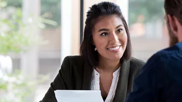 Woman smiling during a meeting, holding a document.