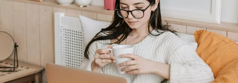 woman sitting on her bed looking at a computer screen