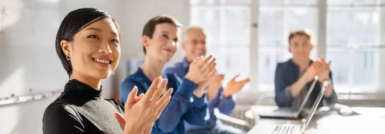 A group of office workers of different ethnicities and in casual wear, chatting and laughing on the same table